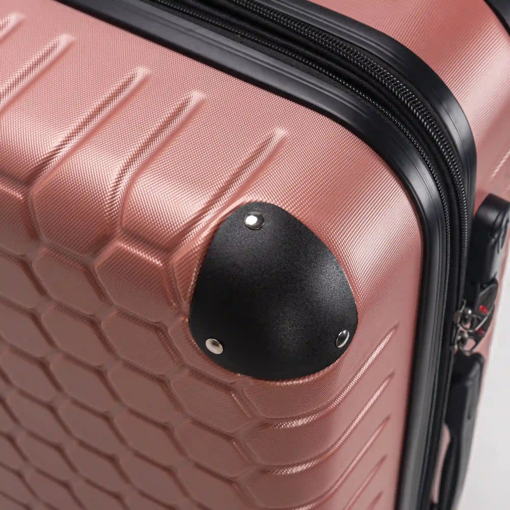 Close-up of a rose gold suitcase with a black handle