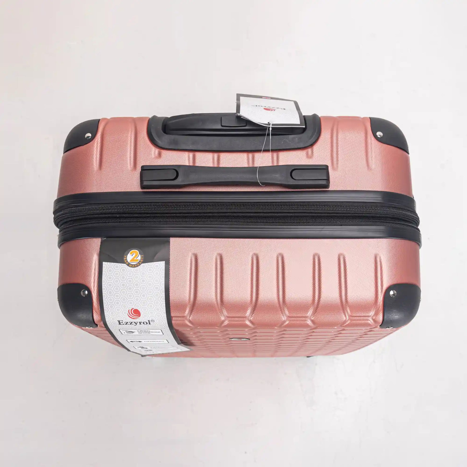 Rose gold suitcase with black handle and wheels on a white background