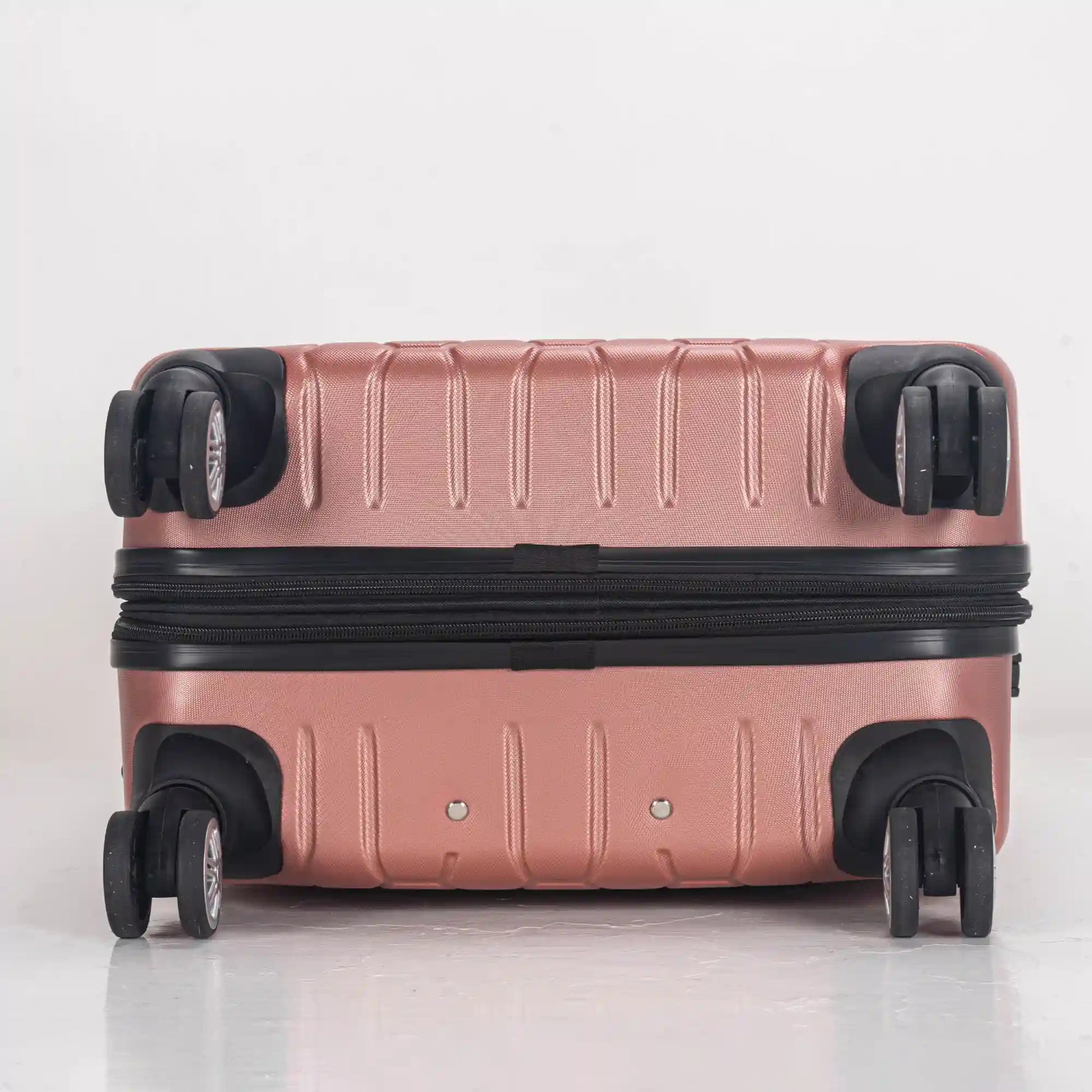 Rose gold suitcase with black wheels on a light gray background