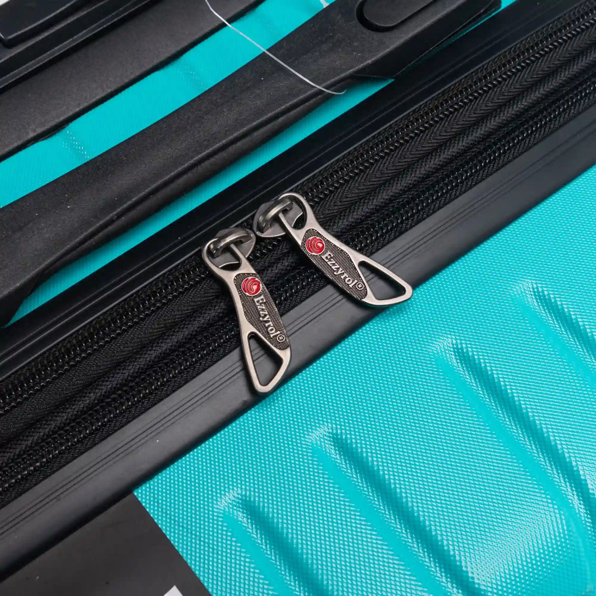 Close-up of a suitcase zipper with a brand logo on a turquoise background