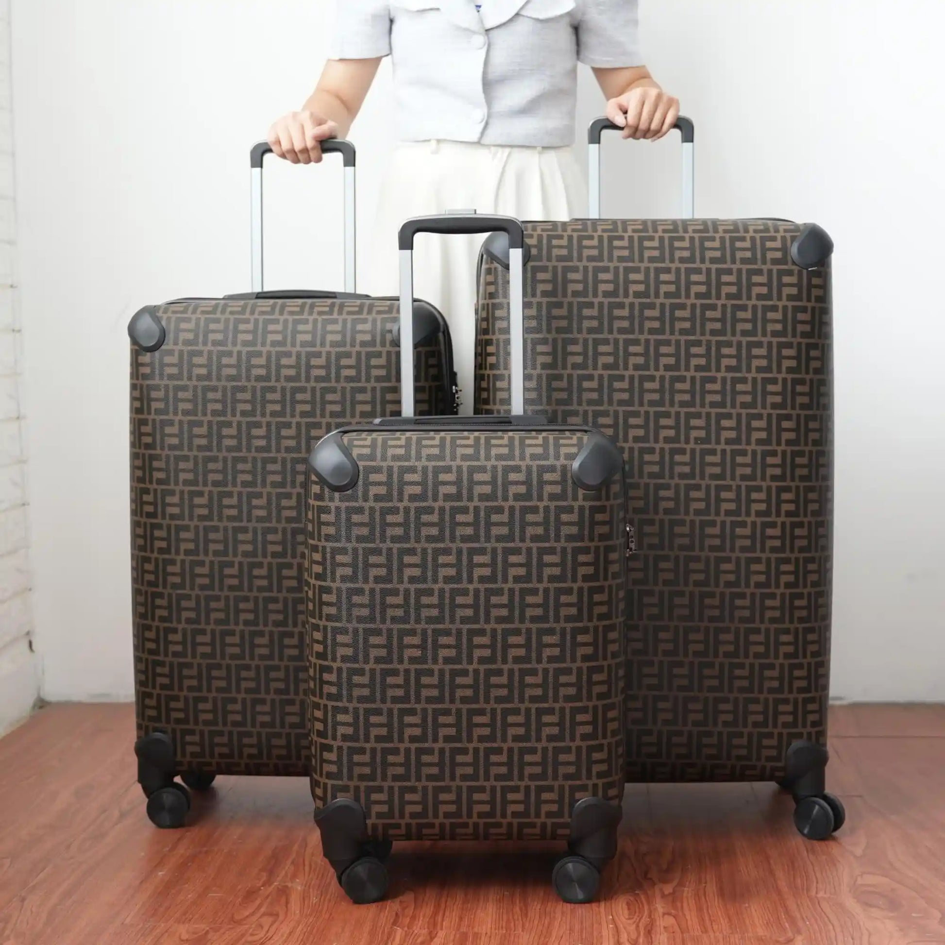 Two patterned suitcases being held by a person on a wooden floor.