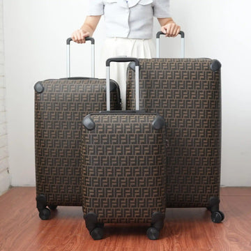 Two patterned suitcases being held by a person on a wooden floor.