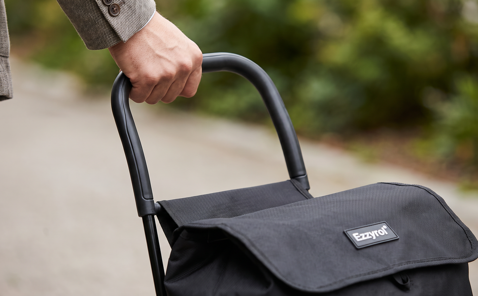 Hand resting on the handle of the black Ezzyrol stair climber trolley outdoors