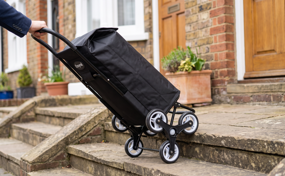 Ezzyrol 74L 6-wheel stair climber shopping trolley in black being pulled up a flight of stone steps