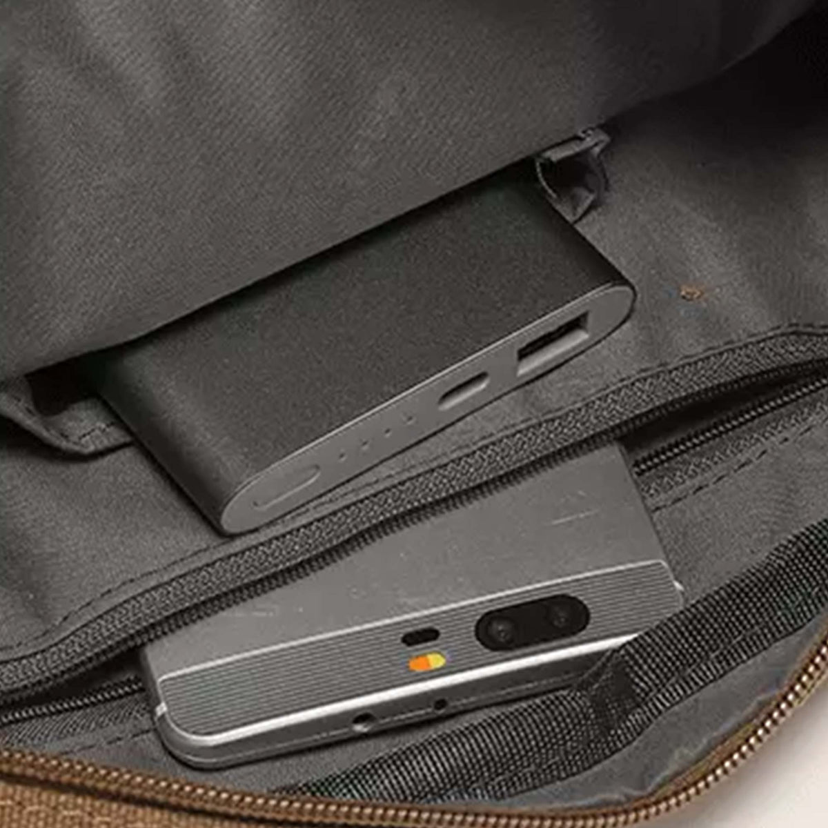 Interior of the Grant crossbody bag showing a power bank and a phone in separate slip pockets