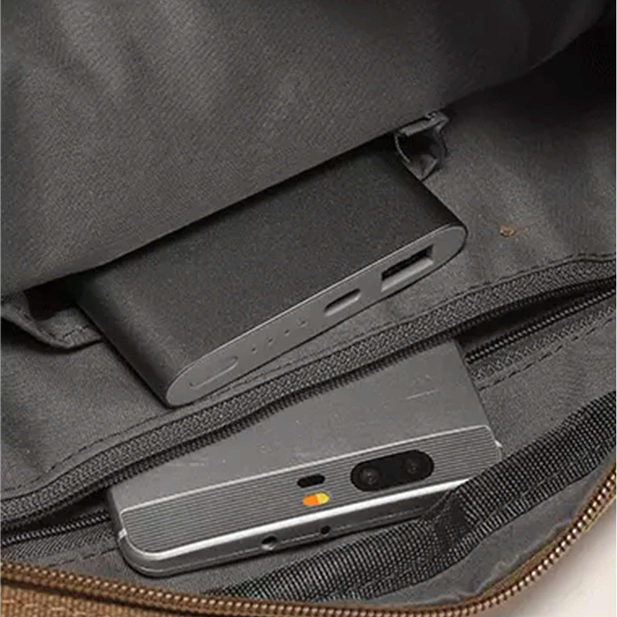 Inside the Grant canvas crossbody bag, a power bank and a phone held in the slip pockets