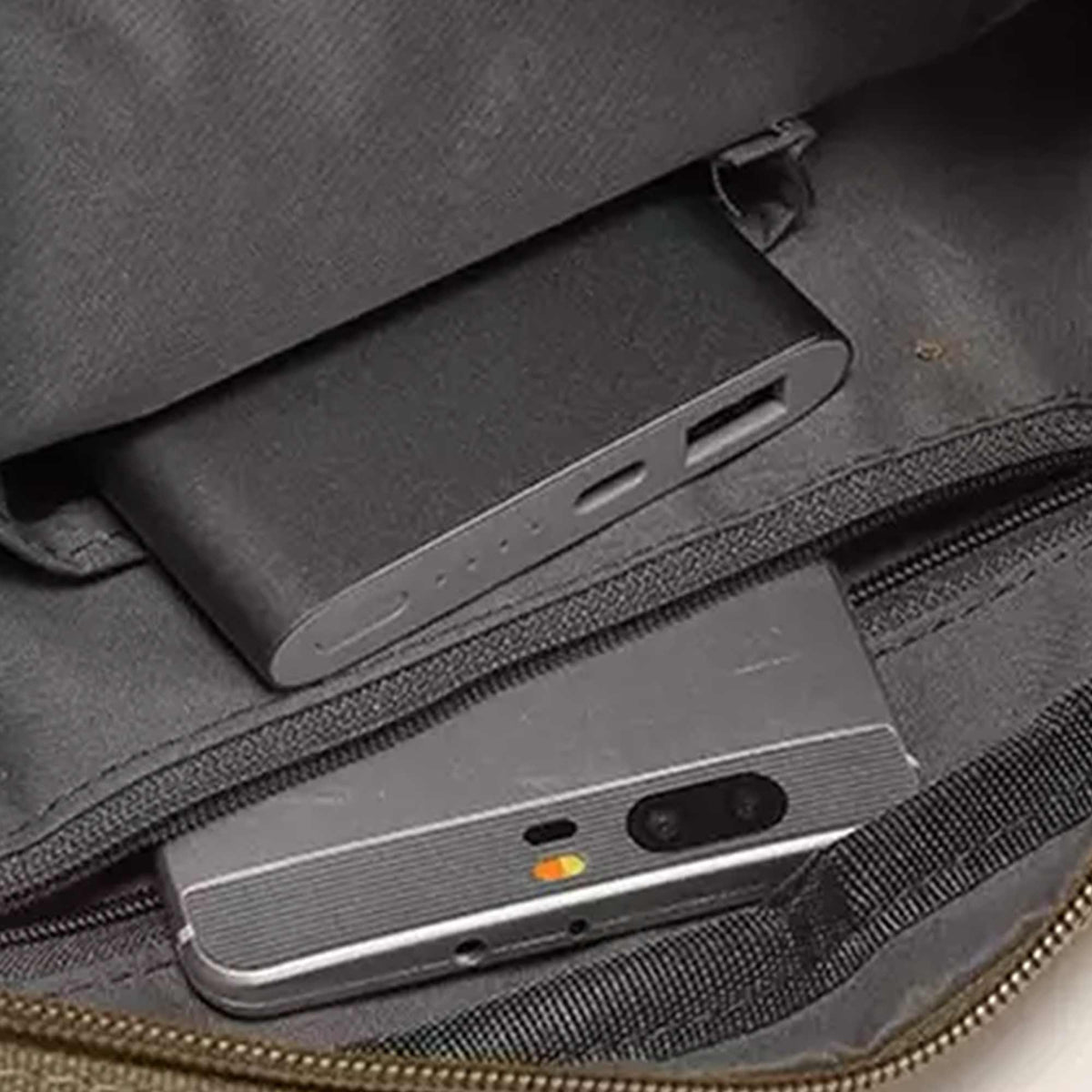 Inside the olive Grant crossbody bag with a power bank and a phone in the pockets