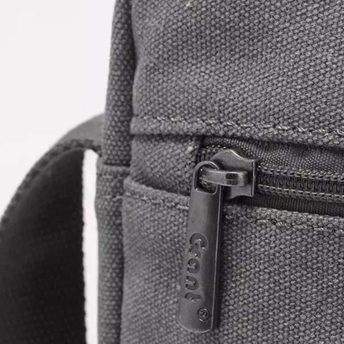 Close-up of the zip pocket and stamped Grant zip pull on the grey canvas crossbody bag