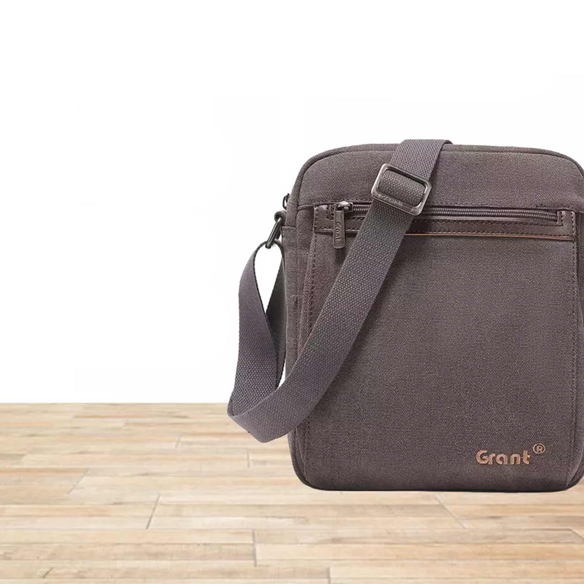 Grant compact canvas crossbody bag in dark brown canvas, front view on a wooden floor
