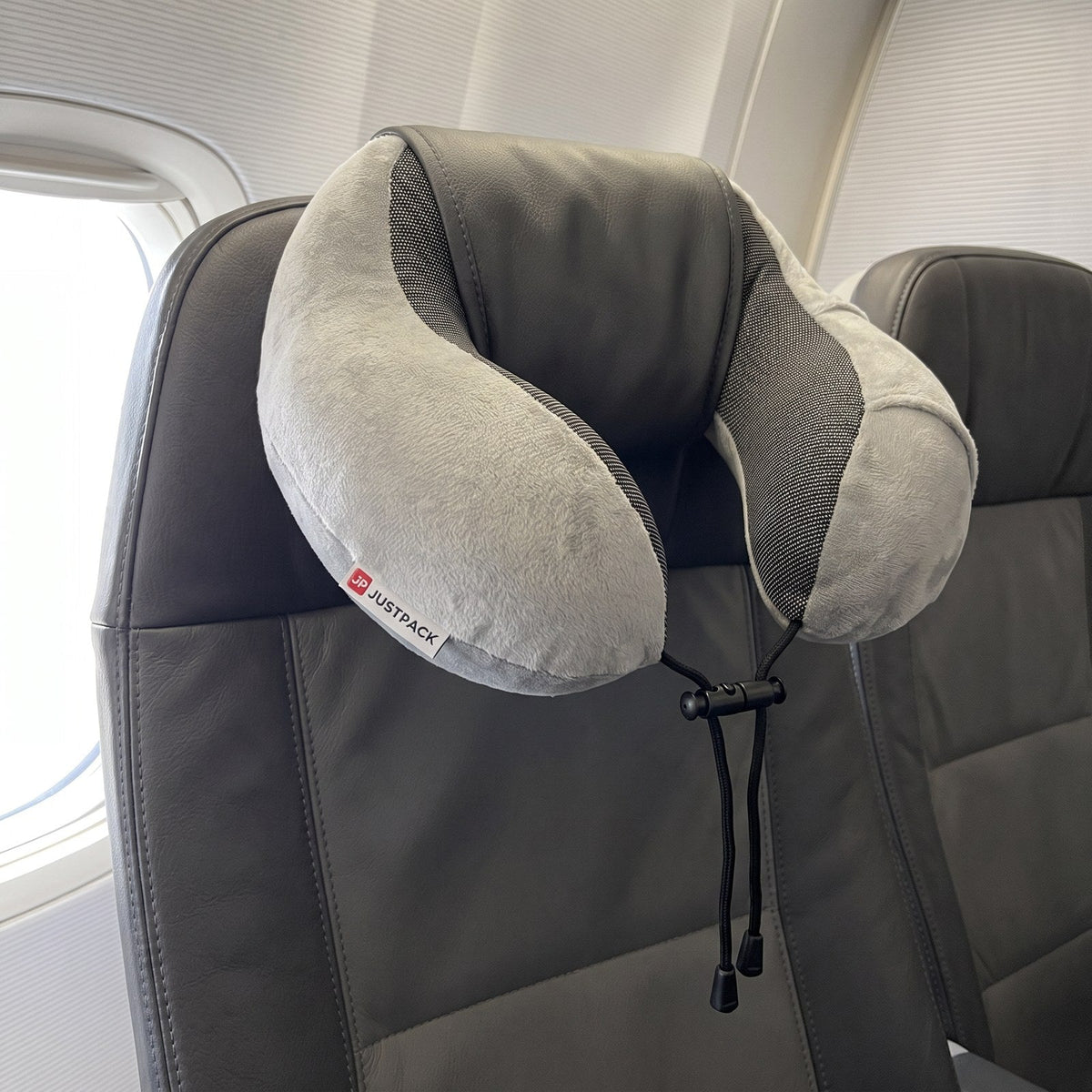 JUSTPACK Drift travel neck pillow in light grey, ready on travel seat