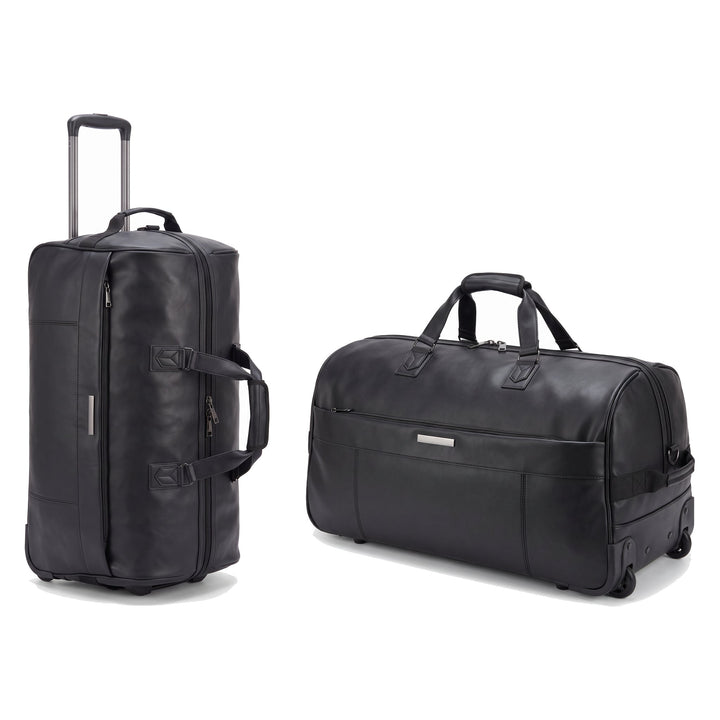 JUSTPACK Belgrave wheeled holdall in black faux leather, shown standing on its wheels with the trolley handle extended and lying at an angle